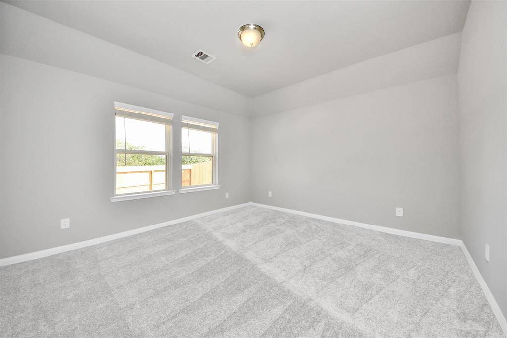 Escape to tranquility in this spacious primary room, adorned with plush carpeting and bathed in the soothing hues of warm paint colors, creating a cozy retreat for relaxation.