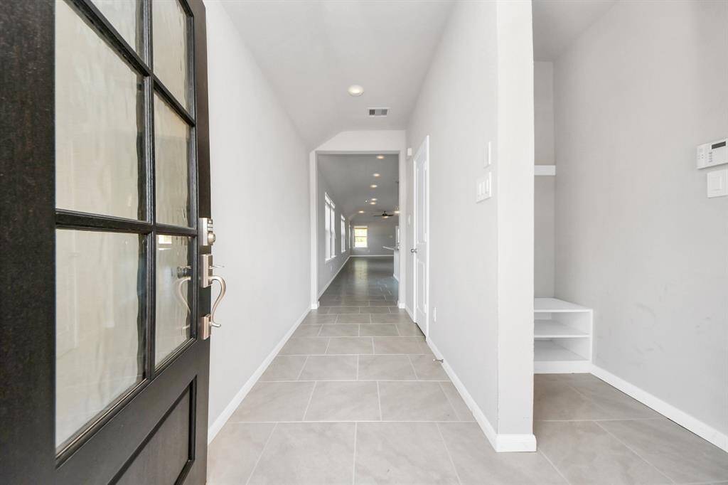 Indulge in luxury as you step into the threshold of this breathtaking home. Greeted by a glass front door, the grand entrance beckons with its soaring ceilings, adorned with vinyl plank flooring with sleek oversized baseboards.