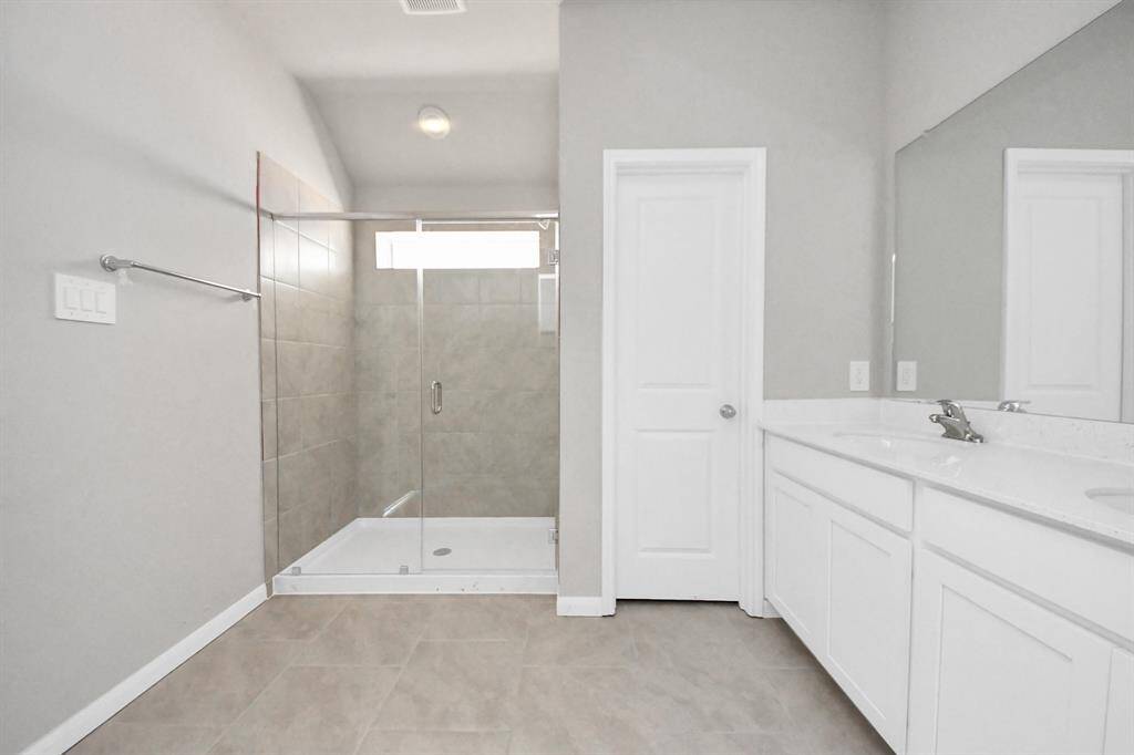 Enhance your daily routine at the refined vanity area, which boasts dual sinks, sleek countertops in soft, light tones, and modern fixtures. The bright, stylish lighting adds a touch of sophistication, creating a luxurious atmosphere that complements the entire space.
