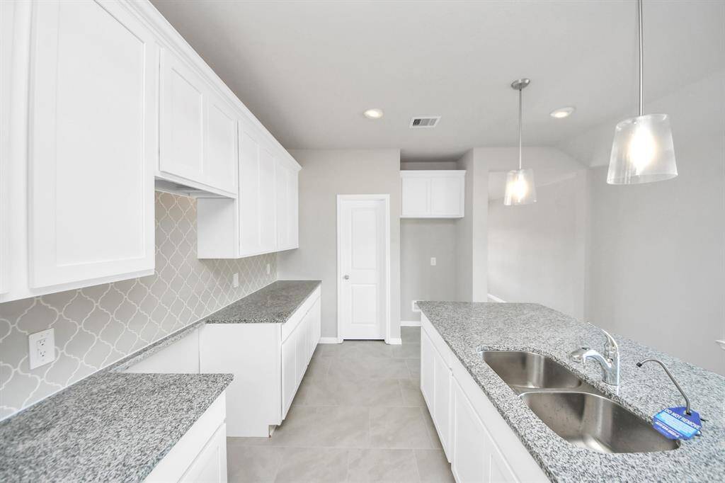 The kitchen is a culinary haven, featuring granite countertops, a tile backsplash, stainless steel appliances, and 42” upper cabinets.