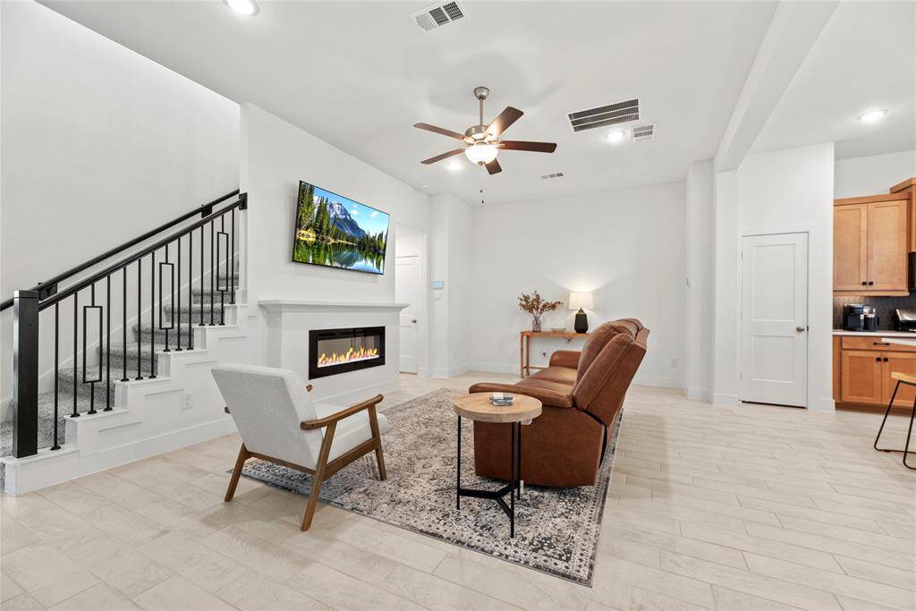 The family room boasts an electric fireplace, ceiling fan and high ceiling.