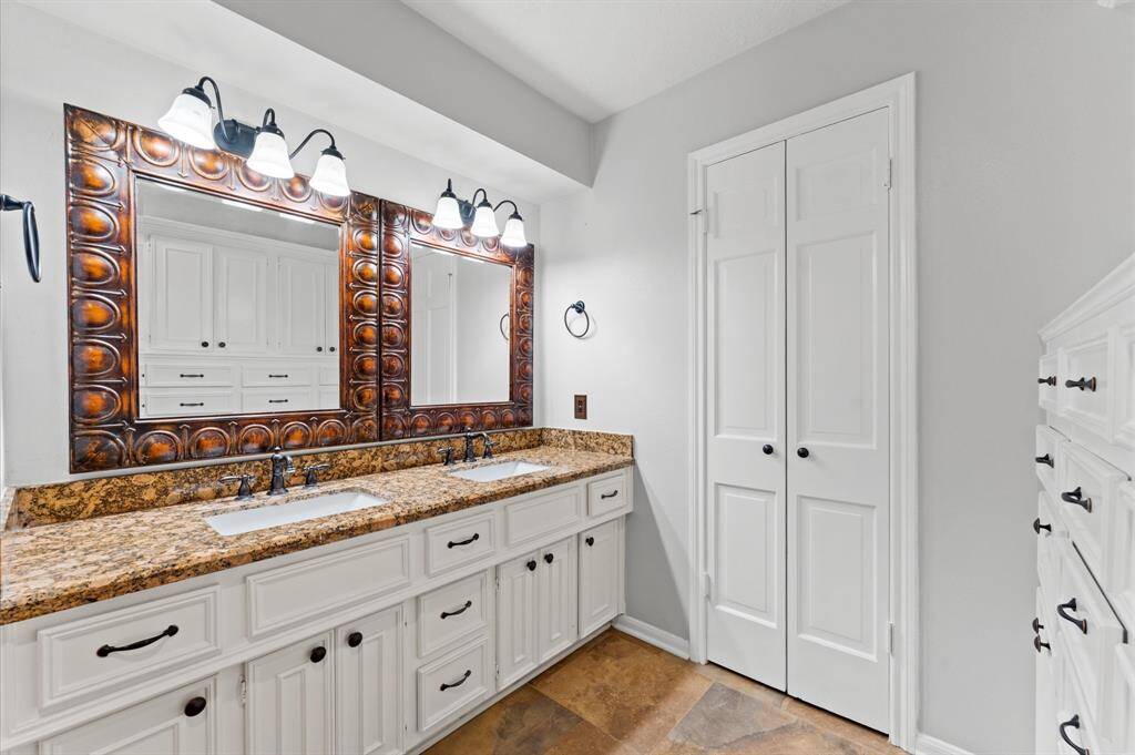 Primary bathroom offers double sinks and at opposite wall, you have built in drawers.
