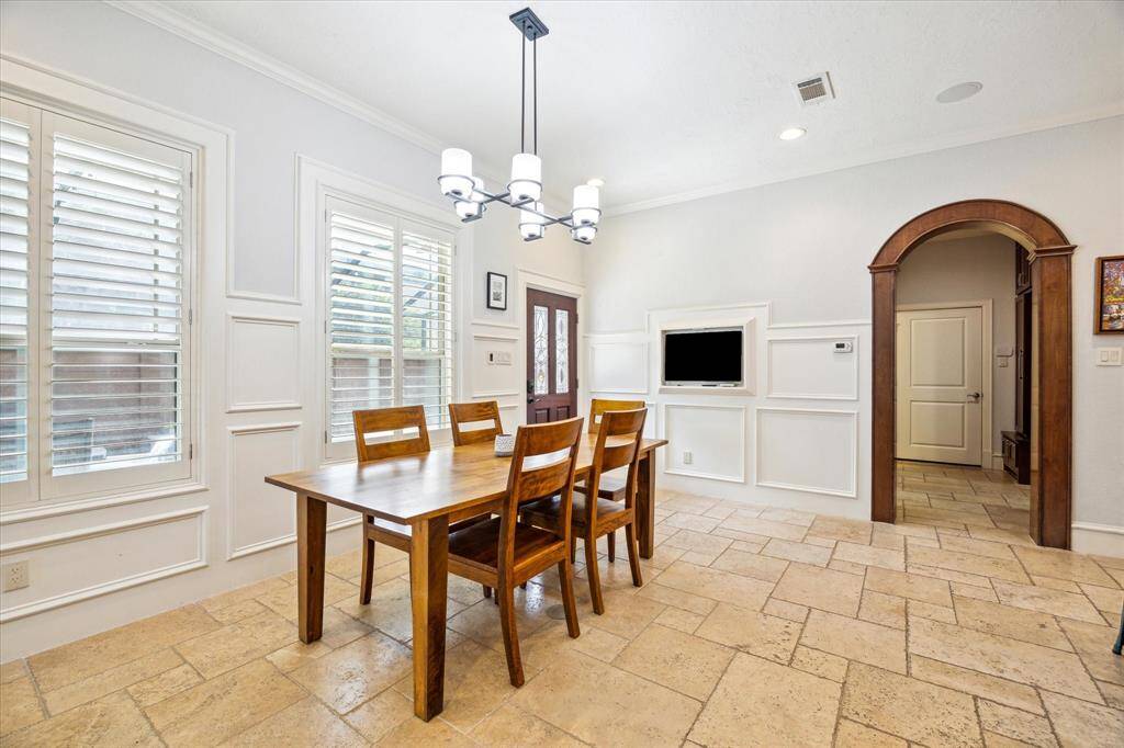 The dining room seamlessly opens into the kitchen, offering views of the pool and outdoor kitchen. Also pictured is the hallway leading to the garage, which includes a spacious walk-in pantry, large laundry room, and a convenient mudroom.