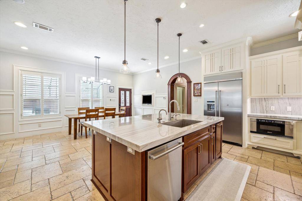 With travertine flooring, stainless steel appliances, and picturesque pool views, this kitchen combines elegance and functionality. The large 48" KitchenAid refrigerator adds luxury, with an additional refrigerator conveniently located in the laundry room.