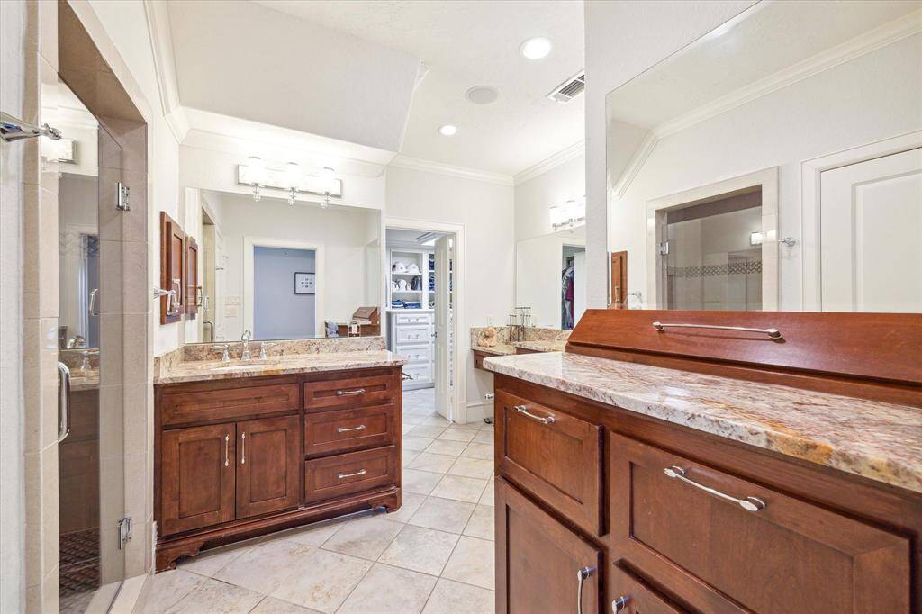[Primary Bathroom] The primary bathroom boasts custom cabinetry, a large walk-in shower, dual separate sinks, ample vanity space, and a spacious walk-in closet.