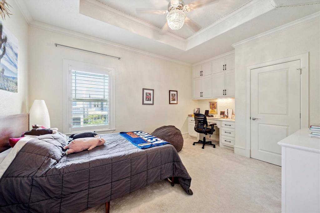 [One of the four guest bedrooms] This guest bedroom features tray ceilings, a large window, and a custom-built work area—ideal for studying or a quiet workspace. Walk-in closet.