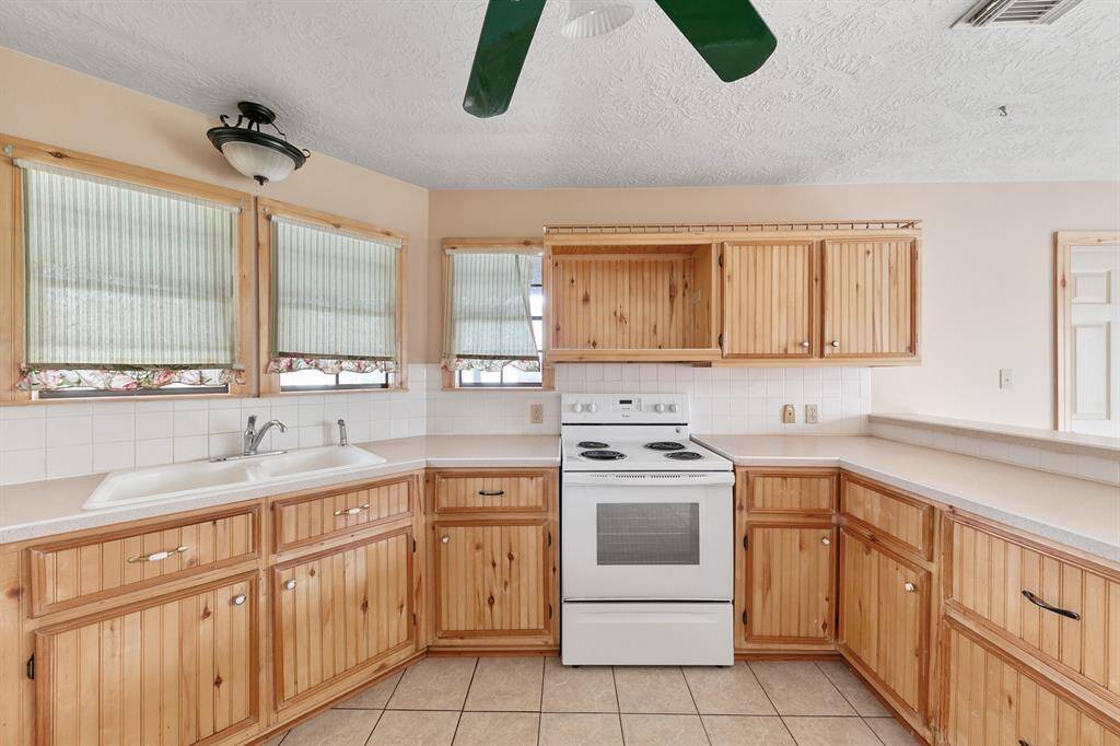 The kitchen features natural wood cabinets that add warmth and character, offering both style and functionality for storage and organization.