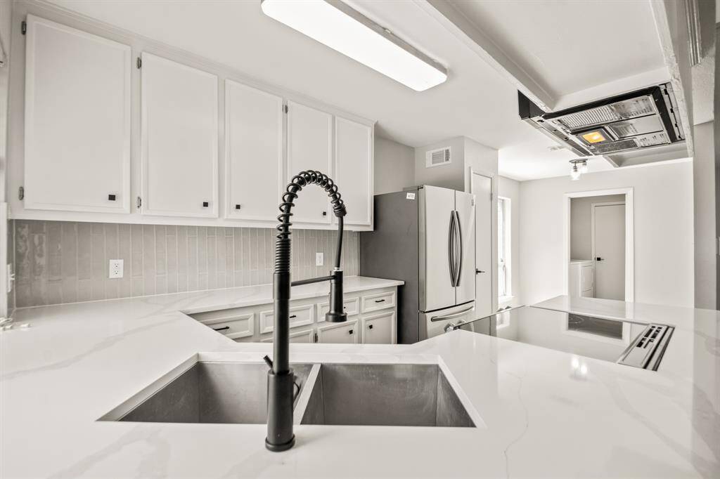 The kitchen features sleek quartz countertops that wrap around the side wall, providing ample prep space and a seamless flow.
