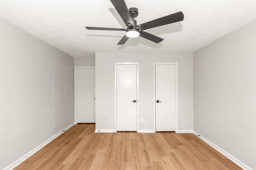 Secondary bedroom #1, across from the primary bedroom, features updated LVP flooring, new fan, fresh paint and a walk-in closet with double doors.