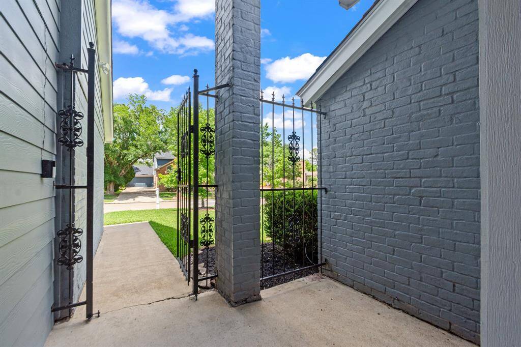 The gated front porch, measuring 11x9, offers a private and inviting space to relax or greet guests. Framed by a black iron gate, it adds charm and functionality to the home’s entrance.