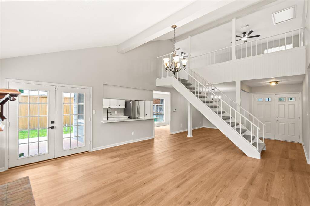 This view of the living room highlights the double French doors leading to the back porch, creating a bright and inviting atmosphere. You’ll also see the open upstairs flex room, the stylish kitchen with wraparound countertops, and a cozy breakfast area.