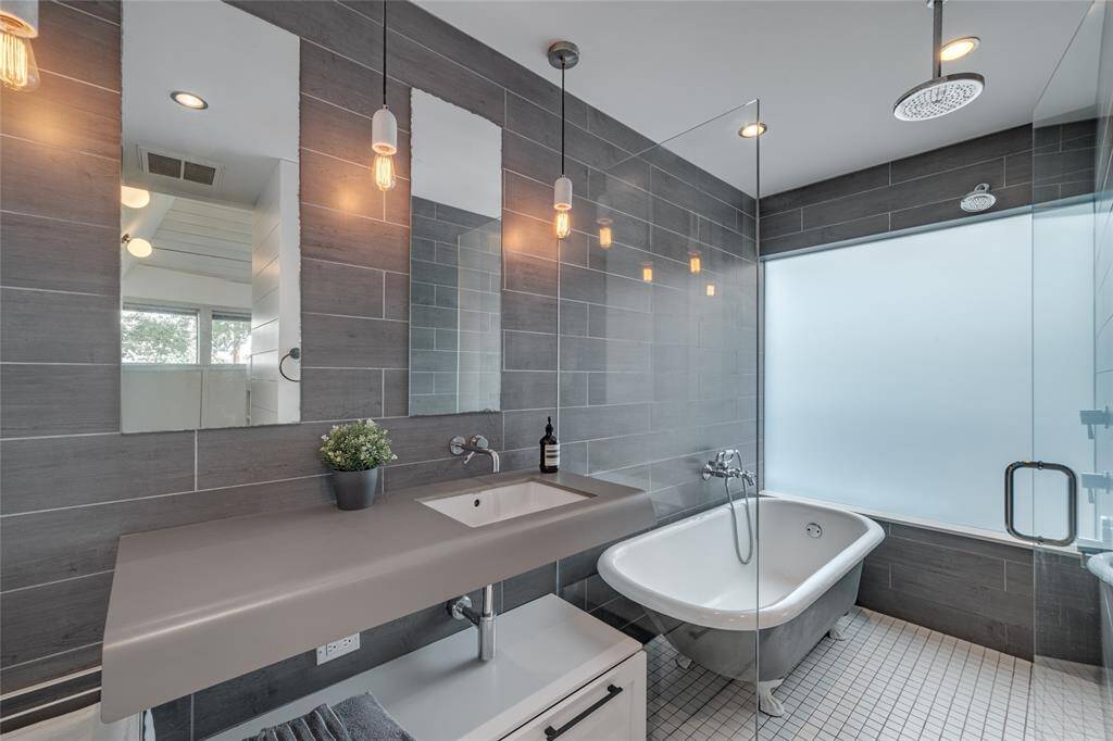 Primary bathroom is another great mix of texture a vintage cast iron tub, glass doors and a quartz counter top. Very clean design.