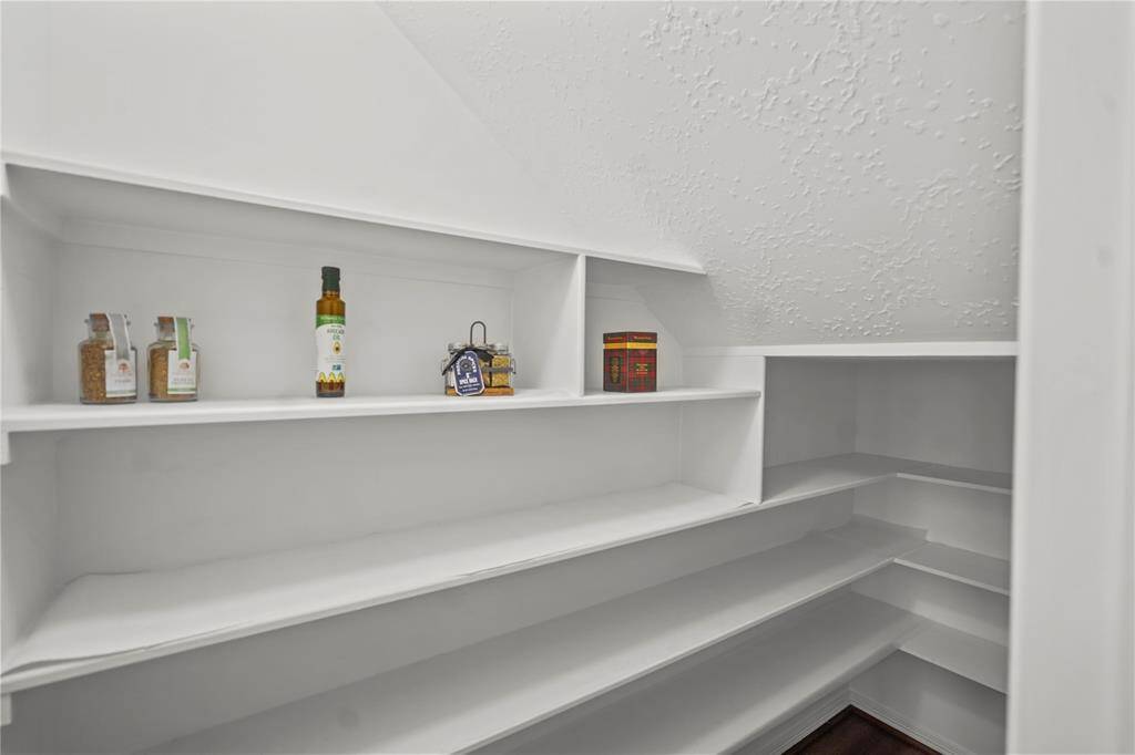 This photo shows a large pantry with white shelves, ideal for storing kitchen essentials and pantry items.