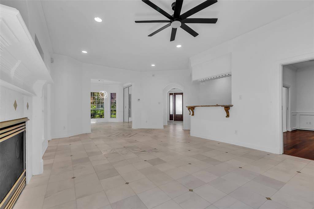 This spacious living area features a clean, white interior with recessed lighting and a modern ceiling fan. It includes a gas log fireplace.