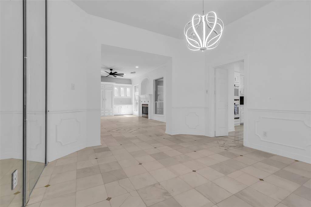 Bright dining area with large windows offering plenty of natural light, modern chandelier, and easy access to the kitchen through a butler doors.