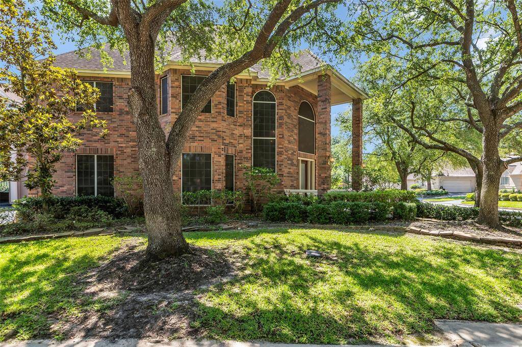 Elegant entrance with a rich brick exterior, featuring a solid wood door with frosted glass panels. The porch has decorative white railings and a sleek, dark tiled floor, providing a welcoming and sophisticated entryway.