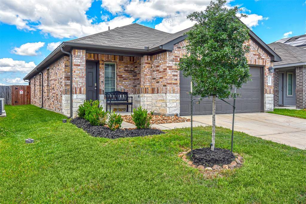 This is a modern, single-story brick home with a two-car garage and a neatly maintained front yard.