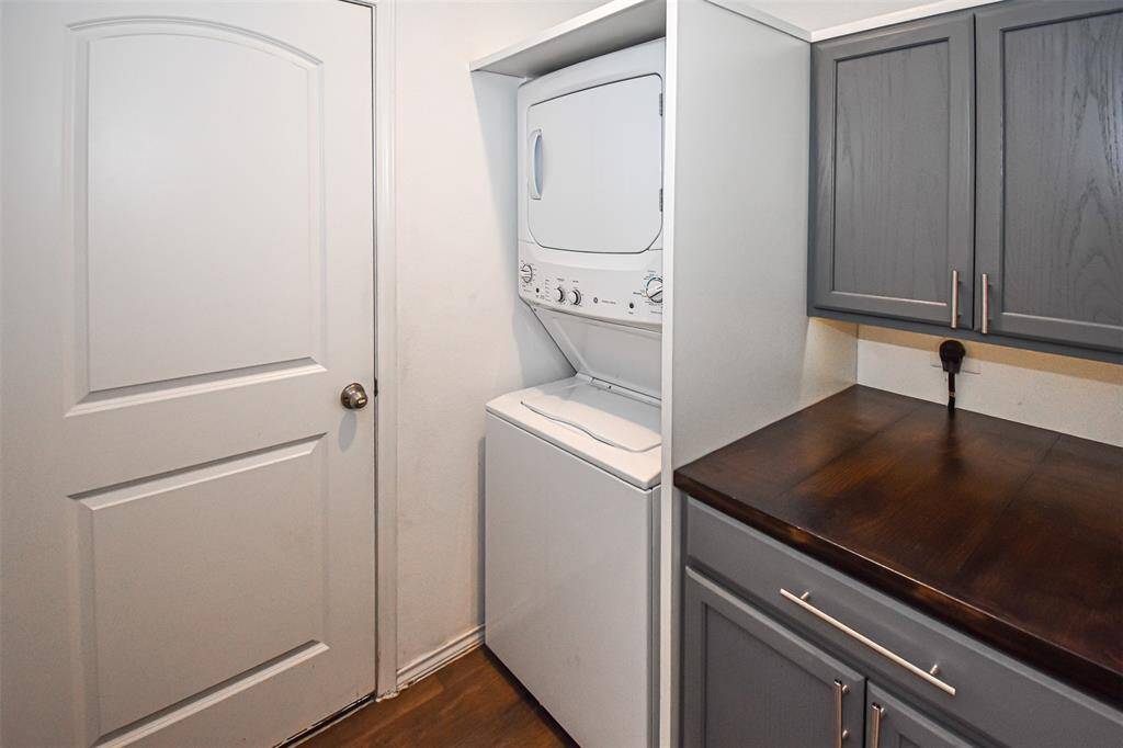 This laundry area with washer and dryer, adjacent to gray cabinets and a wooden countertop, providing efficient storage and workspace.