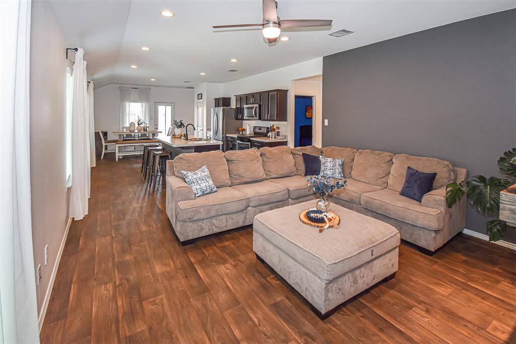This open-concept living area features a spacious layout with a modern kitchen with stainless steel appliances, and a dining area.