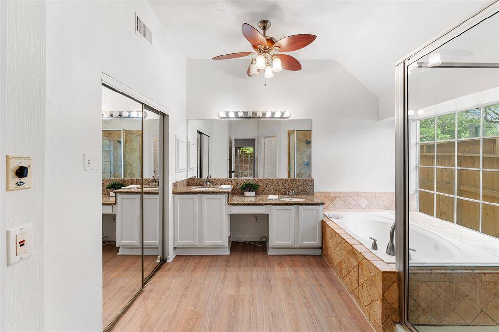 The primary bathroom comes with a shower, spa tub, granite sink, and closet with full-length sliding mirror door.