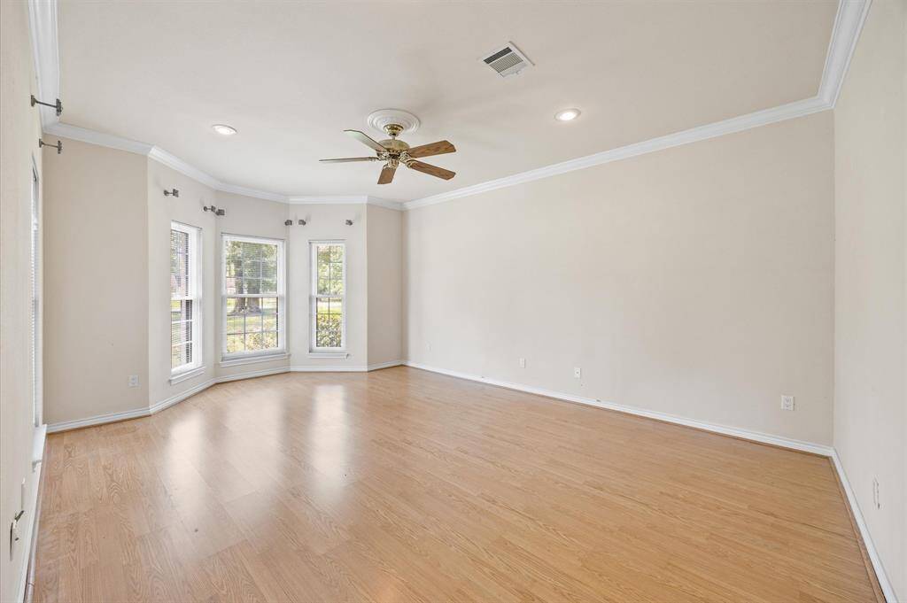Primary suite with bay window, crown molding, & recessed lighting