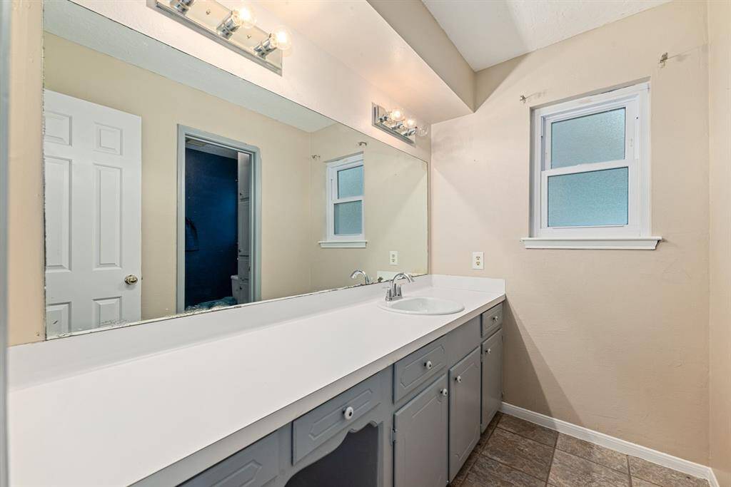 Hall bathroom features a large mirror with a single sink vanity with ample counter space.