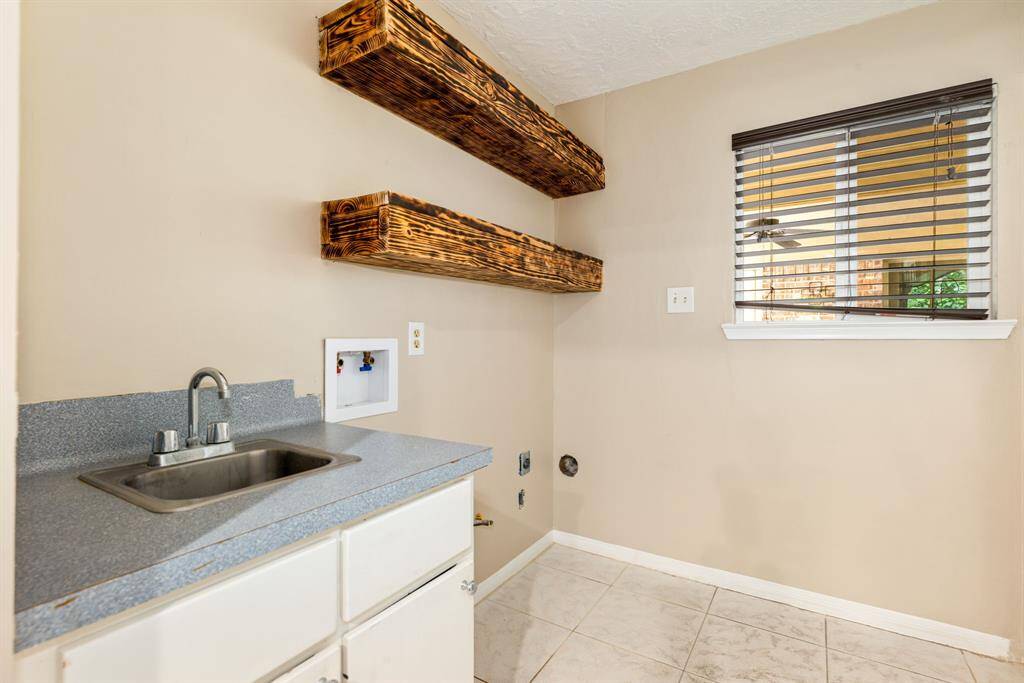 The utility room includes a small sink and countertop, two rustic wooden shelves, and a window with blinds. Located in the main home