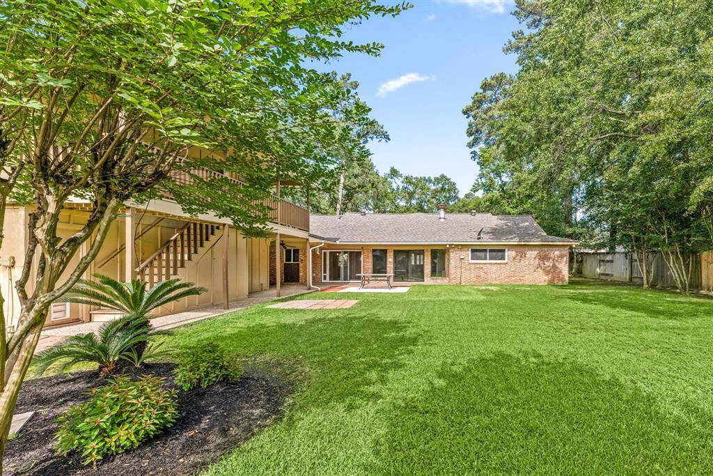 Spacious backyard with lush green lawn and mature trees.