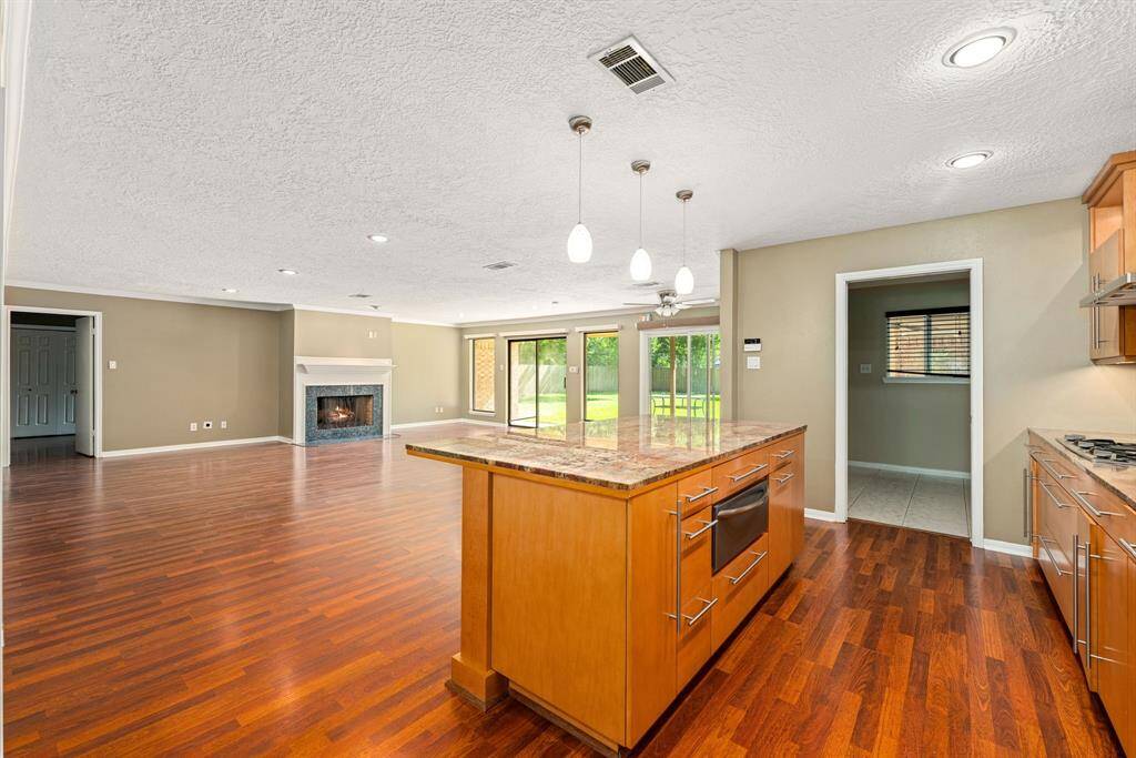 This spacious open-concept living area features large windows offering plenty of natural light and a view of the backyard, creating a welcoming and airy atmosphere.