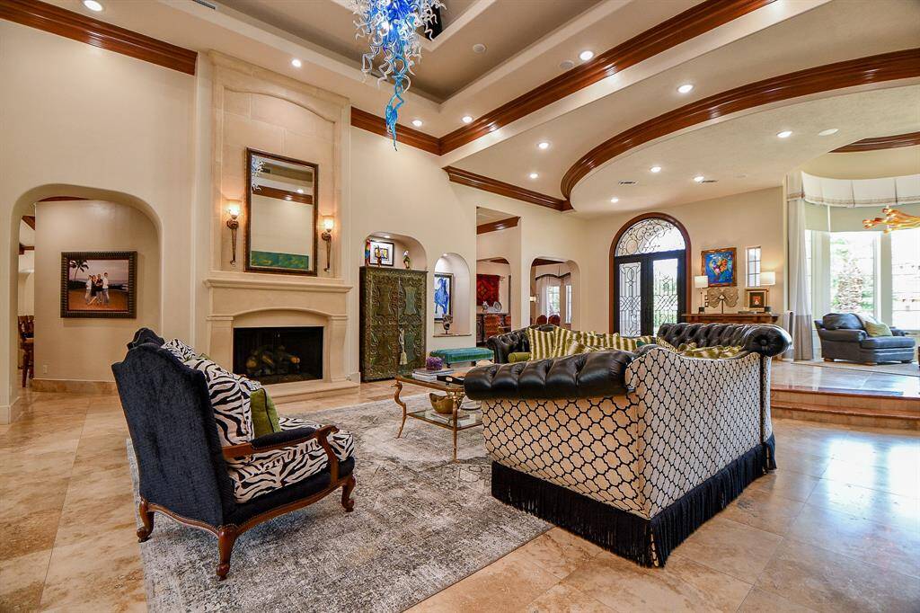 Large living room with grand travertine floors, tray ceiling overlooking the backyard, pool with waterfalls.