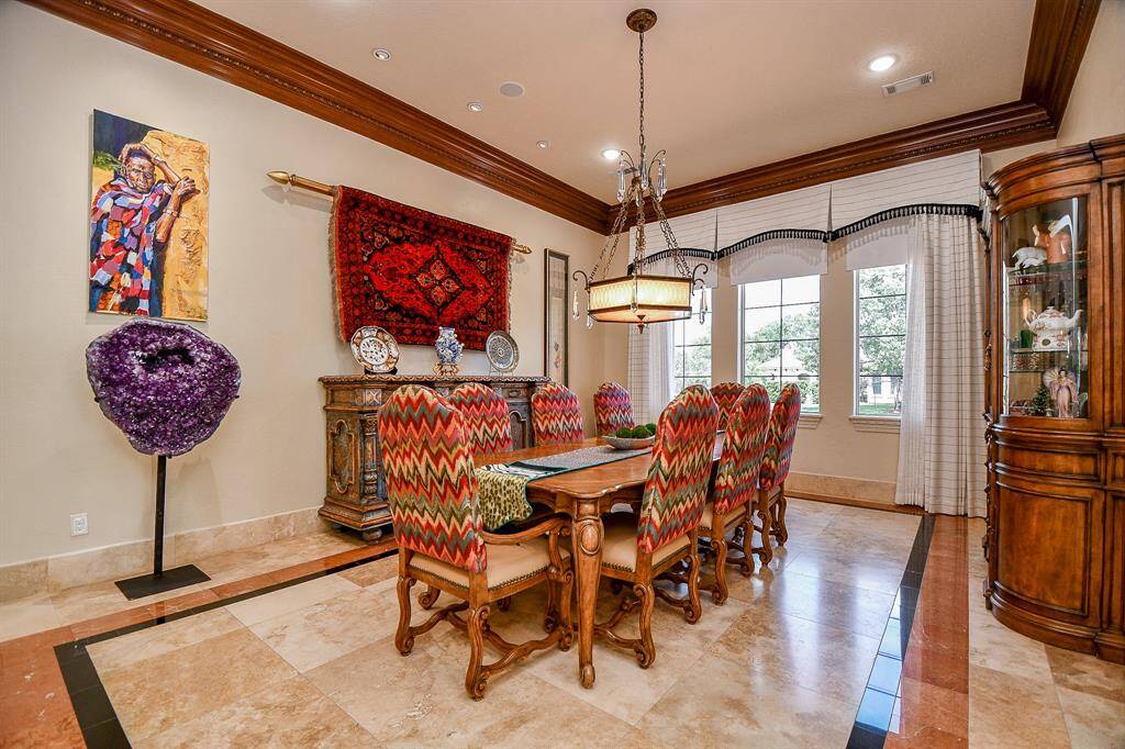 Formal dining room, beautiful travertine floors, large windows with window treatments, crown molding to list a few of the many details.