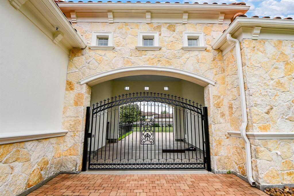 Stucco and stone exterior with driveway gate.