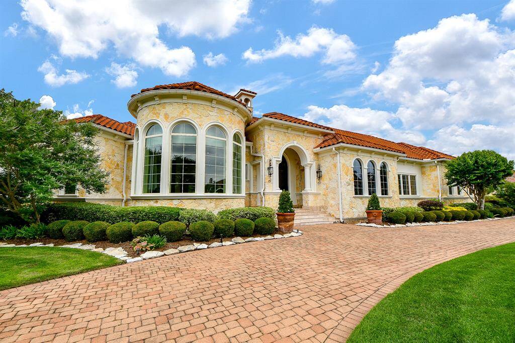 Another view of the home with paved circular driveway and lots of windows providing natural light.