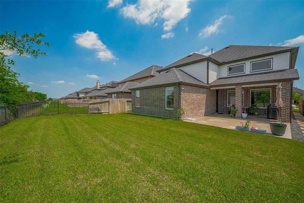 A spacious, well-maintained backyard with a large patio area, perfect for outdoor activities and entertaining. The home features a modern brick exterior and is part of a well-kept neighborhood.