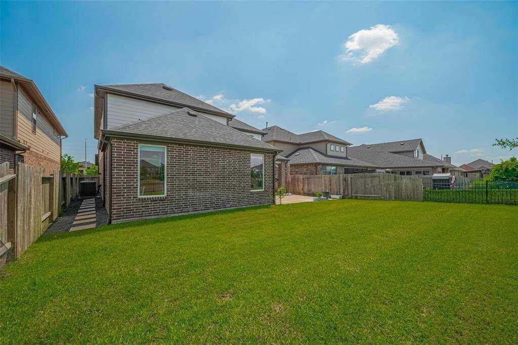 Spacious backyard with well-maintained lawn, surrounded by a wooden fence for privacy. The brick exterior of the house adds charm, and there's a small patio area, ideal for outdoor activities and entertaining.
