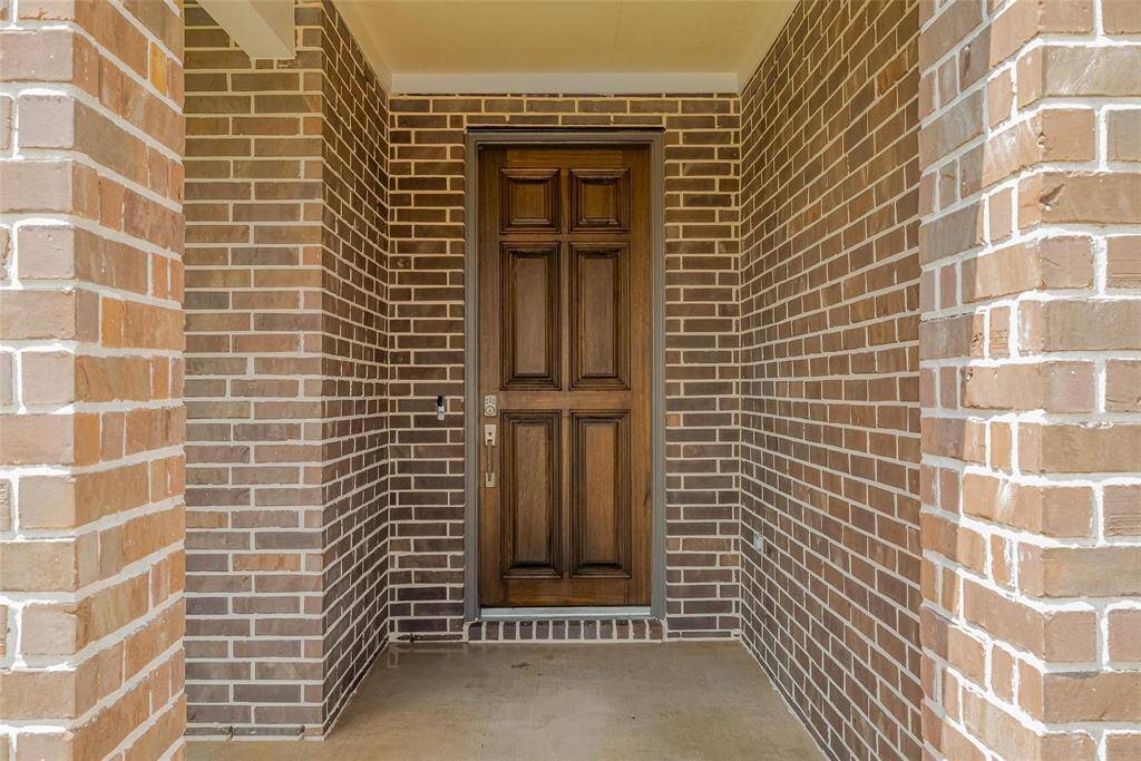This photo features a welcoming front entrance with a sturdy wooden door and classic brickwork, creating a warm and inviting entryway to the home.