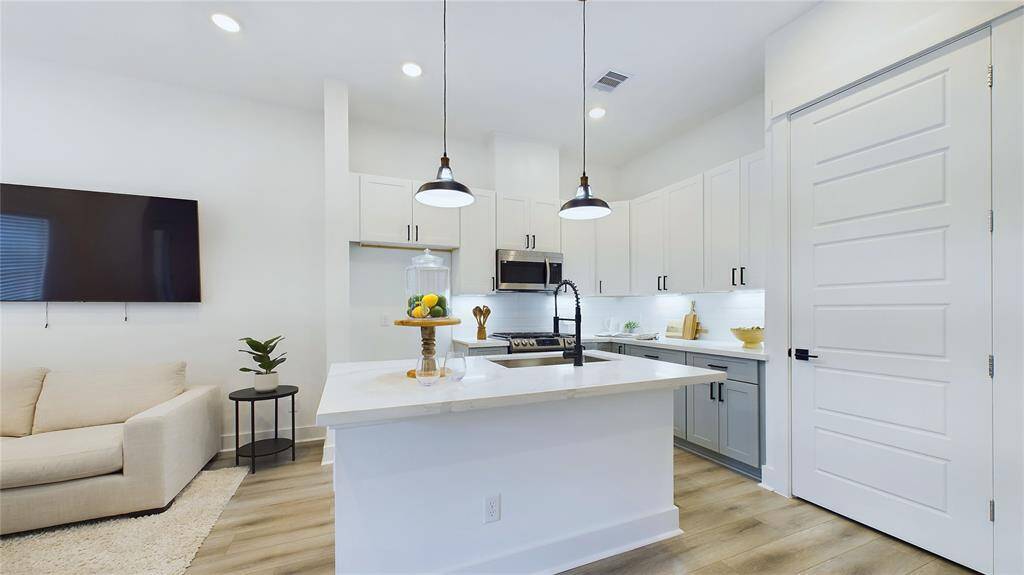 This spacious kitchen boasts an elegant quartz island with a stainless-steel sink.