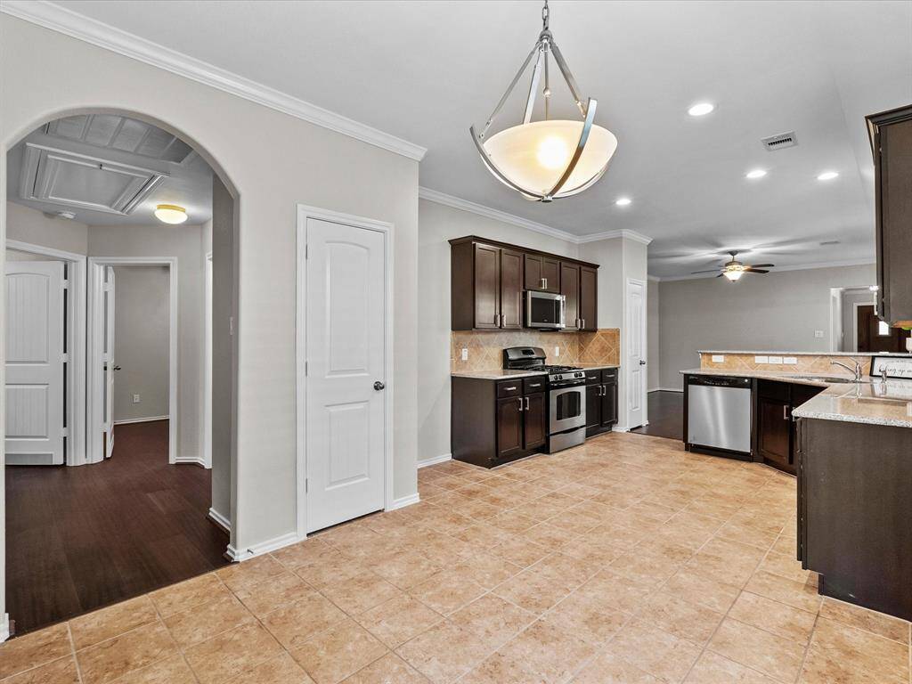 From the breakfast area, see the full kitchen layout with pantry door and a hallway leading to the secondary bedrooms and bath - part of a thoughtful split floor plan that offers added privacy for the primary suite.