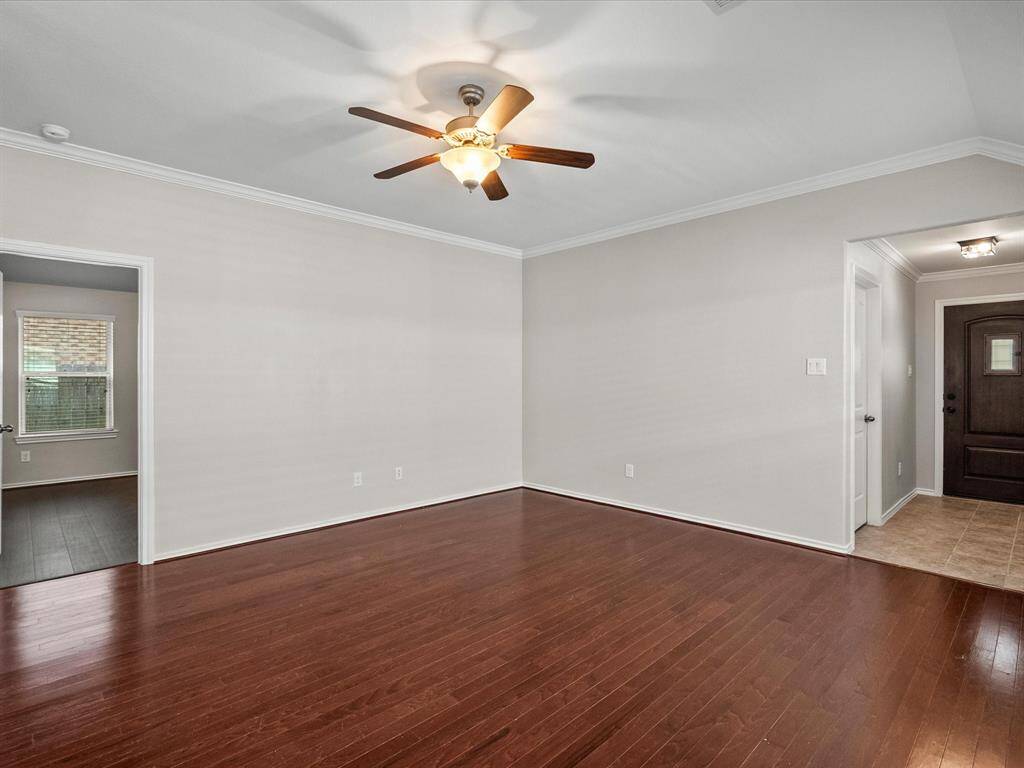 Warm hardwood floors anchor the living space, with a clear view of the primary suite entrance and of the front entry with easy access to the laundry room
