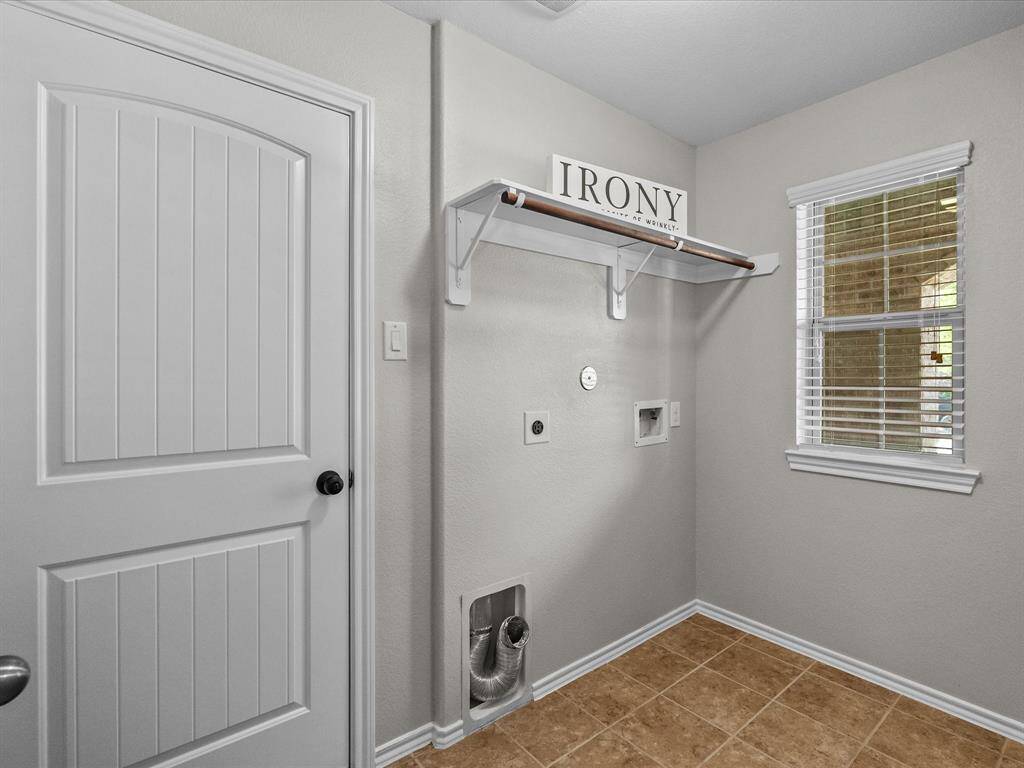 A spacious laundry room with natural light from a front facing window and direct access to the garage - practical and perfectly placed!