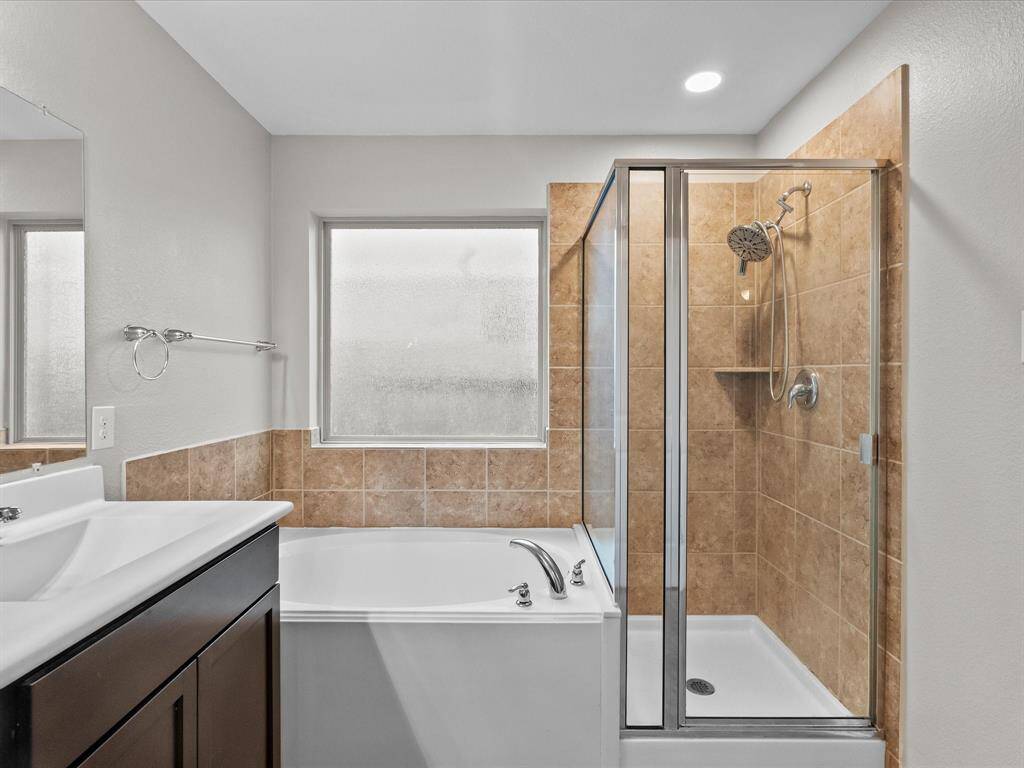 Unwind in the deep soaking tub beneath a large frosted window, or refresh in the walk-in shower with modern fixtures.