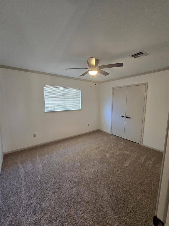 This room is a bright, carpeted space featuring a ceiling fan, a window with blinds, and a double-door closet.