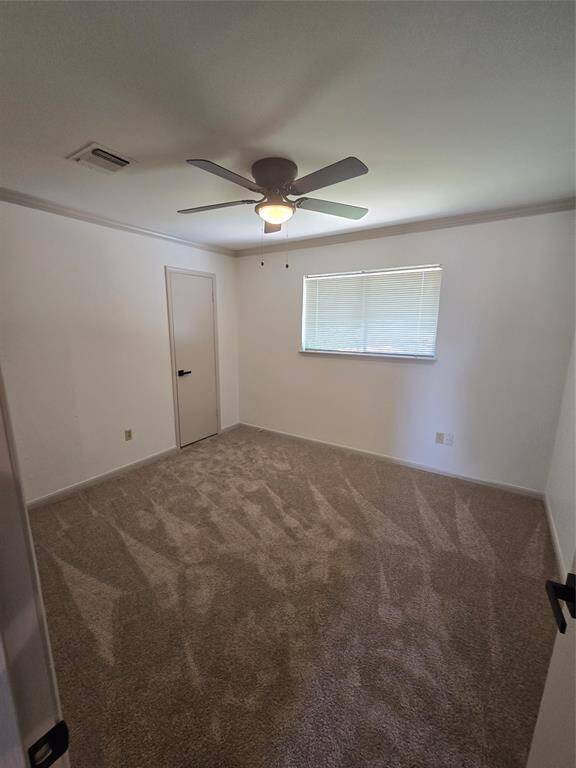 Cozy room with neutral carpeting, a ceiling fan, and a window providing natural light.
