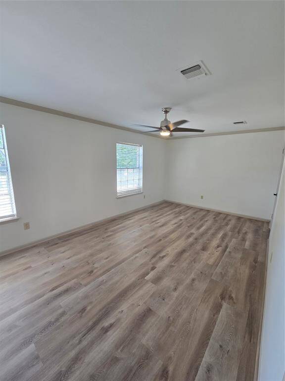 Spacious, bright room with two large windows, light wood flooring, and a ceiling fan, offering a modern and comfortable living space.