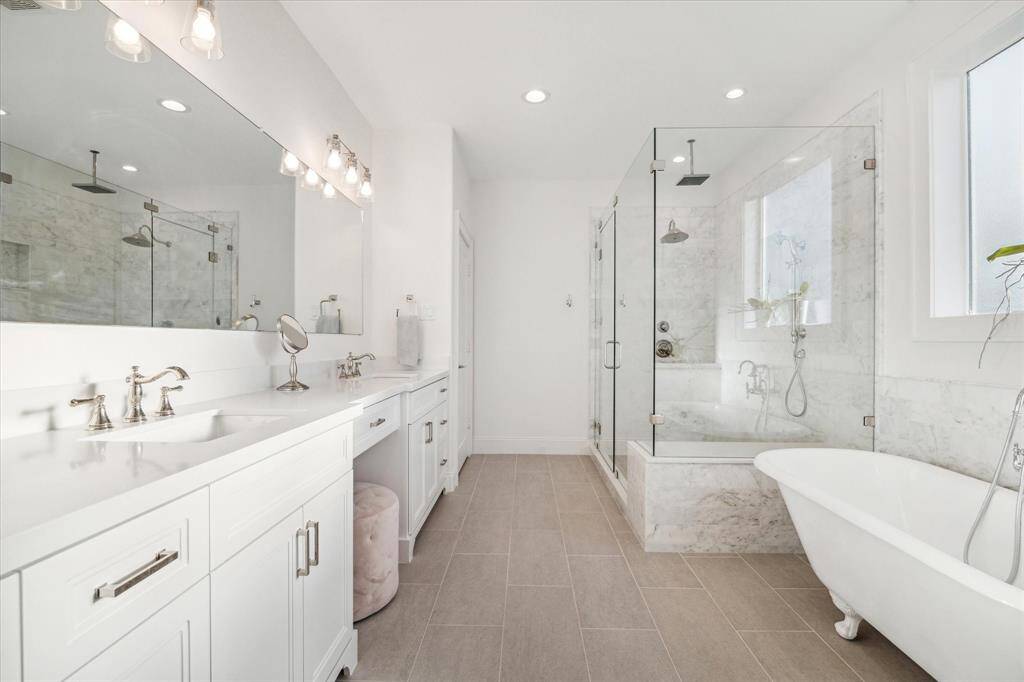 Luxurious primary bath with upgraded tile, stand along clawfoot tub, walk-in shower
