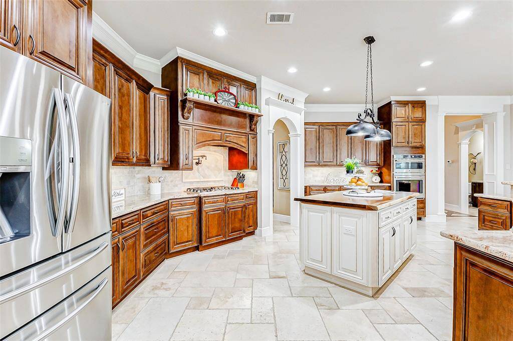 A striking stone tile backsplash adds depth, texture, and a touch of rustic elegance, perfectly complementing the granite and cabinetry for a cohesive and inviting atmosphere.