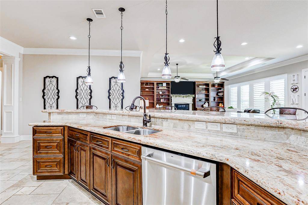 Above, stylish pendant lighting provides the perfect finishing touch, casting soft light over the oversized raised breakfast bar—a welcoming space that bridges the kitchen with the surrounding living and dining areas, encouraging conversation and connection.