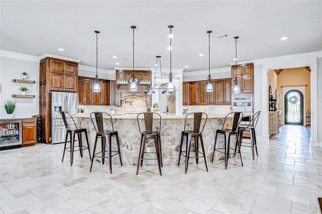 Above, pendant lighting gently illuminates the oversized breakfast bar, making it not only functional for meals but also perfect for entertaining guests or enjoying a casual cup of coffee.