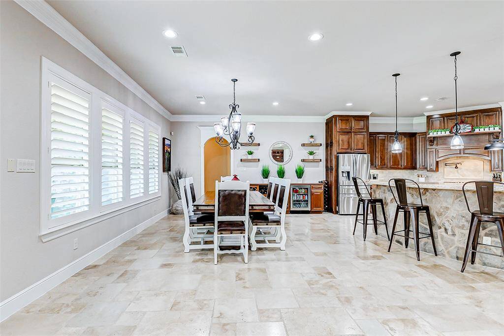 The dining room, seamlessly integrated into this open-concept floor plan, offers a sophisticated yet welcoming atmosphere. The elegant tile flooring flows into the space, while multiple large windows flood the room with natural light, creating a bright and airy ambiance.