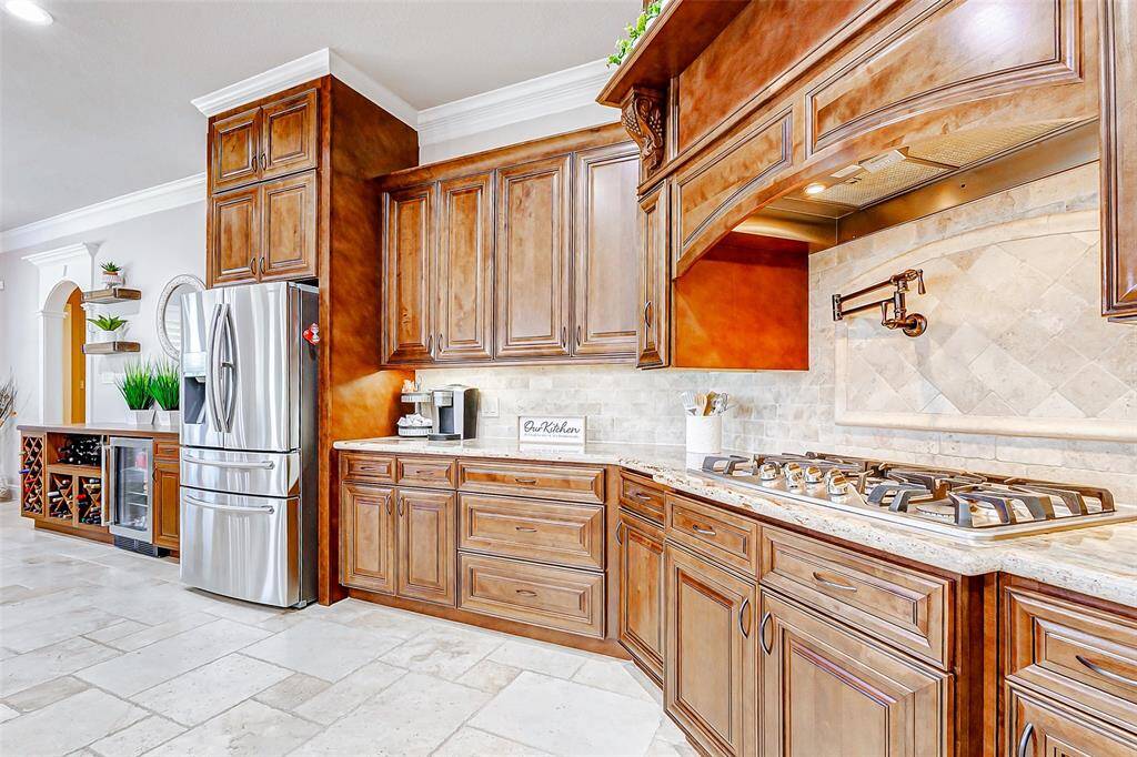 Equipped with high-end stainless steel appliances, this kitchen is a dream for any culinary enthusiast. A top-of-the-line gas cooktop is accompanied by a convenient pot filler, making meal preparation both easier and more efficient. A custom-designed vent hood not only serves its purpose but also acts as a stunning design centerpiece above the cooktop.